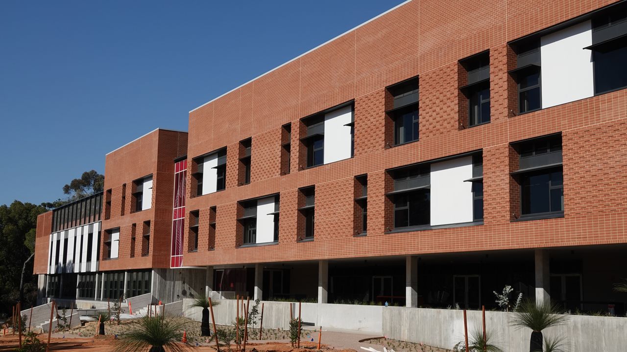 Multi-storey red-brick building with shaded windows and a columned ground floor