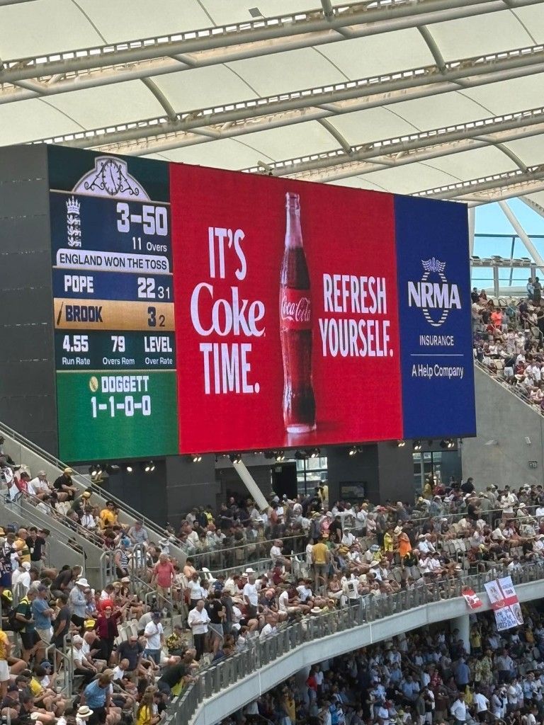 Large-format stadium display showing a live scoreboard and advertising panels