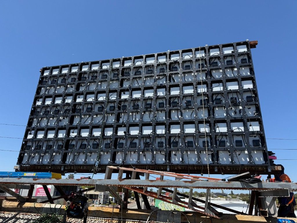 Rear of an outdoor LED cabinet array showing power supplies and cable looms